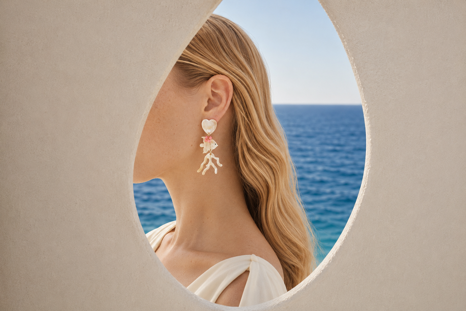 MLO sculptural earring framed by white architecture and the Mediterranean Sea