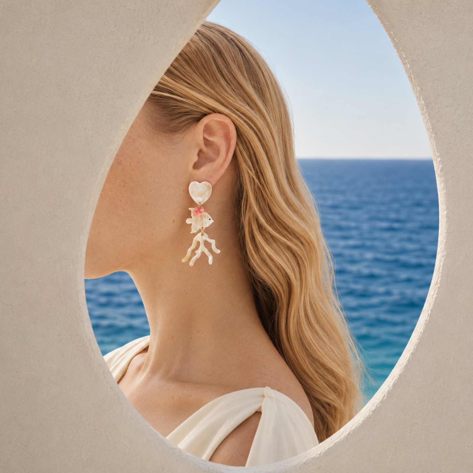 MLO coral and fish earring framed by white architecture and the Mediterranean Sea
